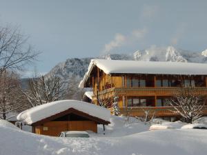 a building covered in snow with mountains in the background at Chiemgau Appartements in Inzell
