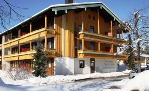 a large wooden building in the snow at Chiemgau Appartements in Inzell