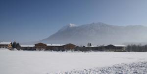 a snow covered field with buildings and a mountain at Chiemgau Appartements in Inzell