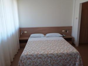 a bedroom with a bed with a blanket and two pillows at Albergo Nyers in Perugia