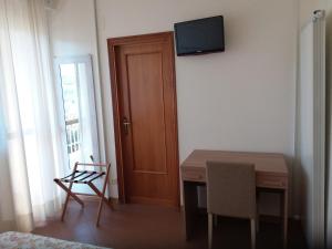 a room with a table and a television on the wall at Albergo Nyers in Perugia