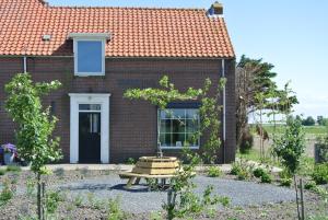 una casa de ladrillo con una mesa de picnic delante de ella en B&B Bouwmanshoeve en Burgh Haamstede