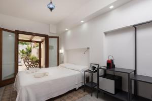 a white bedroom with a bed and a desk at Finisterre in San Vito lo Capo