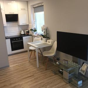 Una sala de estar con una mesa blanca y una cocina. en Apartament Prezydent, en Gorzów Wielkopolski