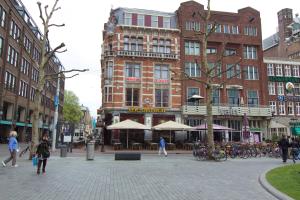 um grupo de pessoas andando em uma rua da cidade com edifícios em City Hotel em Amesterdão