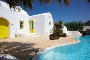 a white house with a swimming pool in front of it at Ftelari Villa in Oia