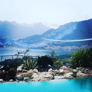 a pool of blue water with mountains in the background at Villa Romele in Pisogne