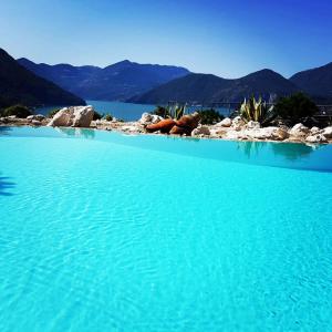 una gran piscina de agua azul con montañas al fondo en Villa Romele, en Pisogne