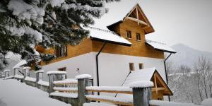 a house covered in snow in front of a fence at Kasiablanka in Szczawnica