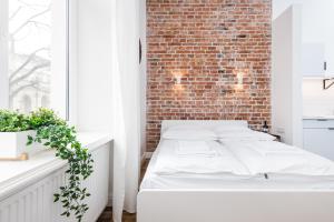 a white bed in a room with a brick wall at Old Time Apartments in Krakow