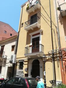 un hombre caminando por una calle en frente de un edificio en Ammaresiamo LTB, en Cefalú