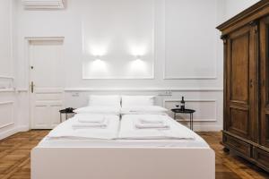 uma cama branca com almofadas brancas num quarto em Old Time Apartments na Cracóvia