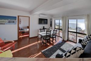 un salon avec un canapé et une table avec des chaises dans l'établissement Luz Beach Ocean Front Apartment, à Luz