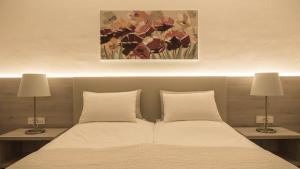 a bedroom with a bed with two lamps and a painting at Hotel Magdalena in Zagreb