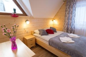 1 dormitorio con 2 camas y un jarrón de flores sobre una mesa en Domki przy Potoku en Suche