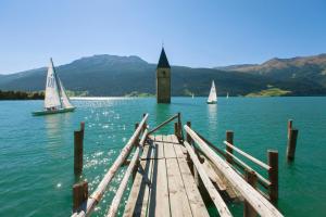 a dock with sail boats on a lake with a tower at Residence Ferienheim Folie in Melago