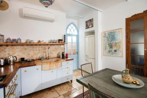 a kitchen with white cabinets and a wooden table at Above The Spring in Jerusalem