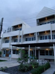 un gran edificio blanco con sillas delante en Albatross Guesthouse @ Thungwualaen Beach, en Pathiu