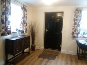 a room with a black door and a table and a window at Windylands in Chipping Sodbury