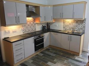 eine Küche mit weißen Schränken und einem Herd mit Backofen in der Unterkunft Luxury Portrush Holiday Homes - The Grange, Portrush Sleeps 13 - 6 bedrooms in Portrush