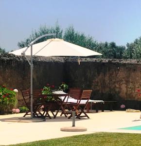 a table with an umbrella and two chairs at ADOBE TYPICAL COTTAGE in AlpalhÃ£o