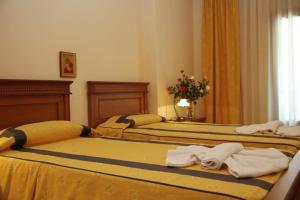 Dos camas en una habitación de hotel con toallas. en Famissi Hotel en Kalambaka