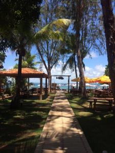 a walkway with picnic tables and umbrellas on the beach at Suíte Bella Vista in Barra Grande