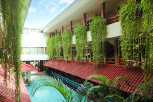 a building with a swimming pool and plants on the side at Hotel Karthi Kuta in Kuta