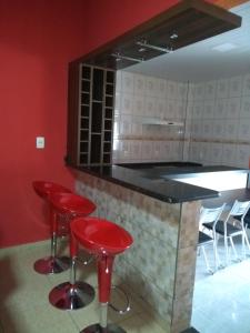 a kitchen with two red stools and a counter at Casa super confortável. in Anápolis