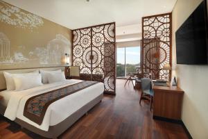 a bedroom with a bed and a desk and a tv at Swiss-Belhotel Airport Jakarta in Tangerang