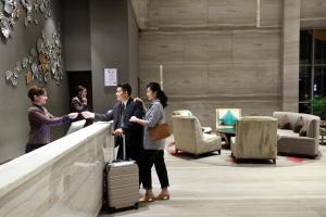 a group of people shaking hands in a lobby at Swiss-Belhotel Airport Jakarta in Tangerang