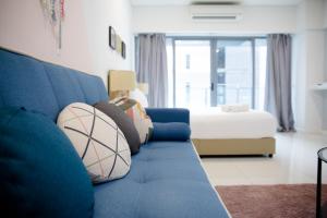 a blue couch in a living room with a bed at Summer Suites by Plush in Kuala Lumpur