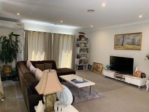 a living room with a couch and a tv at Apple House in Tarneit