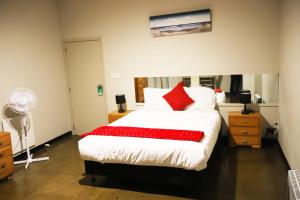 a bedroom with a large white bed with red pillows at Aura Hotel in Wellington