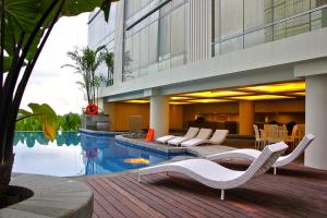 ein Hotel mit einem Pool und Stühlen sowie einem Gebäude in der Unterkunft Lavenderbnb Room 5 at Mataram City in Yogyakarta