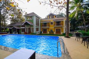 a house with a swimming pool in front of a house at The Amrit Goa in Candolim