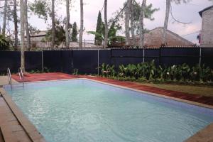 a swimming pool in a yard with a fence at Diyar Villas Puncak M3/47 in Puncak
