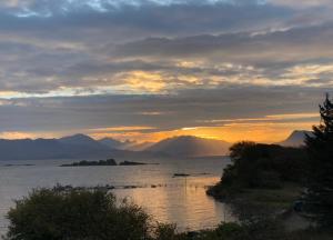 a sunset over a body of water with mountains at Tidal Cottage in Ardvasar