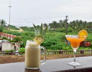 a drink and a glass of orange juice on a table at 'Golden Oceans' 3 bhk beach view villa in Benaulim