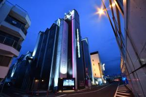 冈山Hotel agehA cinq boutique (Adult Only)的夜晚城市街道上的一栋高楼