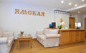 una mujer de pie en un escritorio en una habitación con sillas en Hotel Yamskaya, en Zavidovo