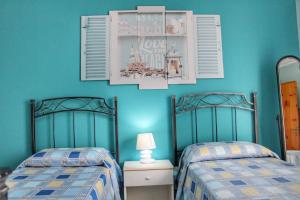 2 camas en una habitación con paredes azules en casa Elisa, en Torre San Giovanni