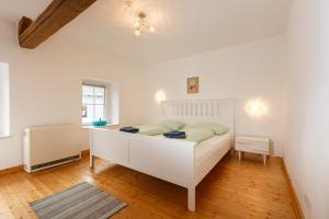 a bedroom with a white bed in a room at Auszeit-Eifel Eifelhaus "Burgaß 1807" Sauna & Badezuber in Willwerscheid