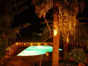 a swimming pool at night with palm trees and lights at Kissamos Hotel in Kissamos