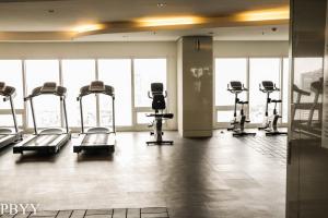 a gym with several tread machines in a room with windows at Green Residences Staycation by PBYY with Complimentary breakfast for 2 in Manila