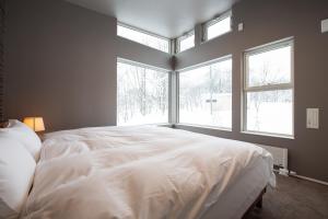 a large white bed in a bedroom with windows at Mountain Butterfly in Niseko