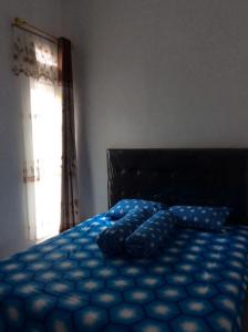 Bett mit blauer Decke und Fenster in der Unterkunft Villa Mutiara Batu in Batu