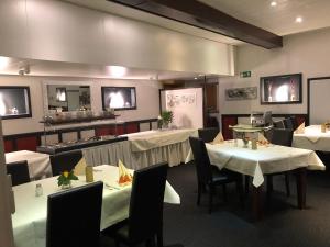 a restaurant with tables and chairs with white table cloth at Hotel & Restaurant Blume in Wolfsburg