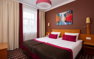 Habitación de hotel con cama grande con almohadas moradas en Oktiabrskaya Hotel, en San Petersburgo