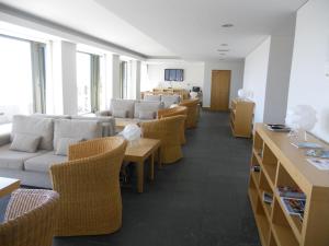una sala de espera con sofás, mesas y sillas en Azores Youth Hostels - São Jorge, en Calheta
